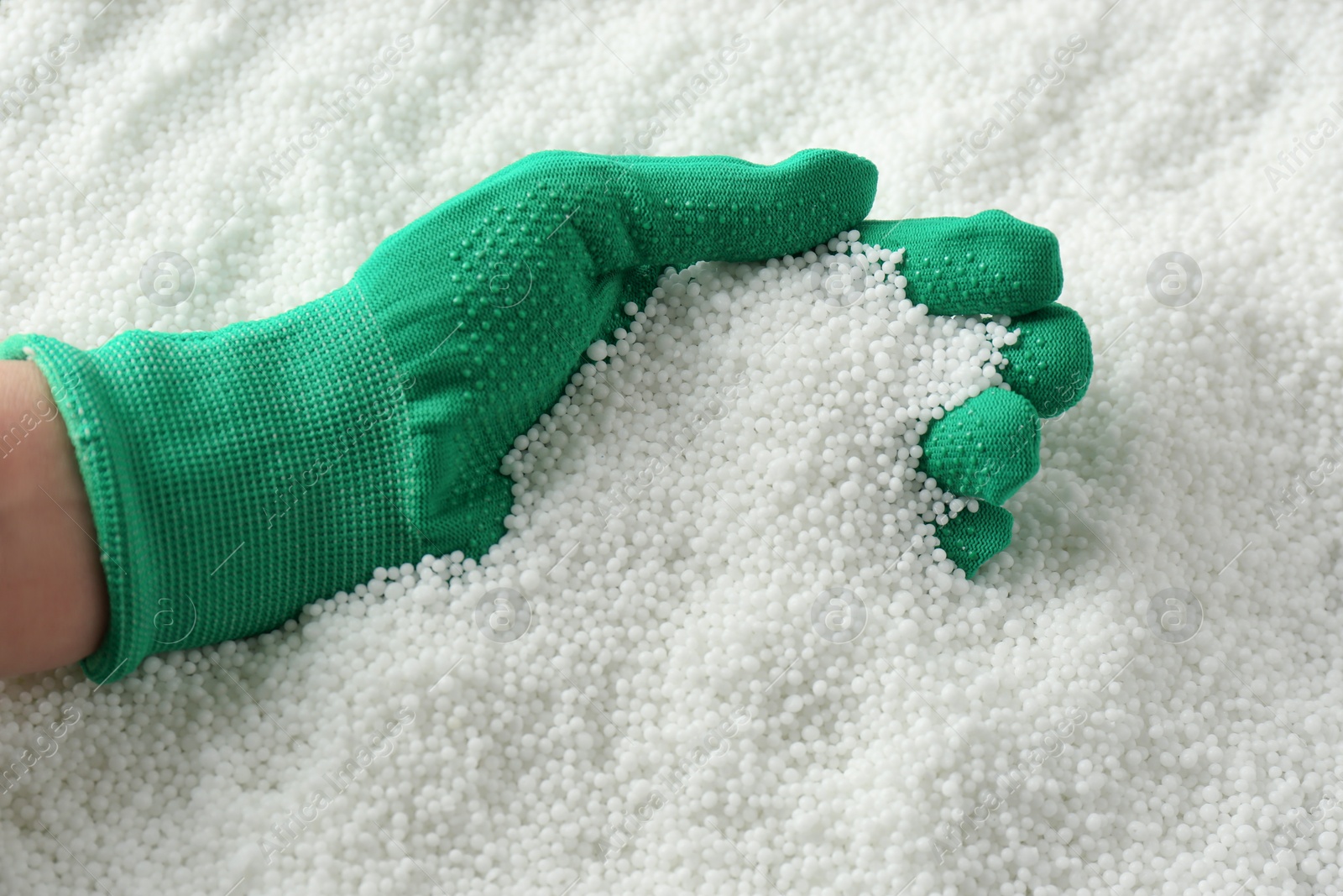 Photo of Farmer taking pellets of ammonium nitrate from pile, closeup. Mineral fertilizer