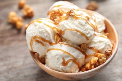 Photo of Tasty ice cream with caramel sauce and popcorn in bowl on table, closeup