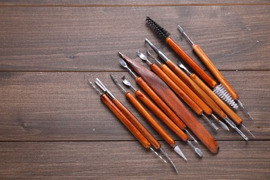 Photo of Set of different clay crafting tools on wooden table, flat lay. Space for text