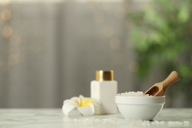 Sea salt and wooden scoop on white marble table, space for text