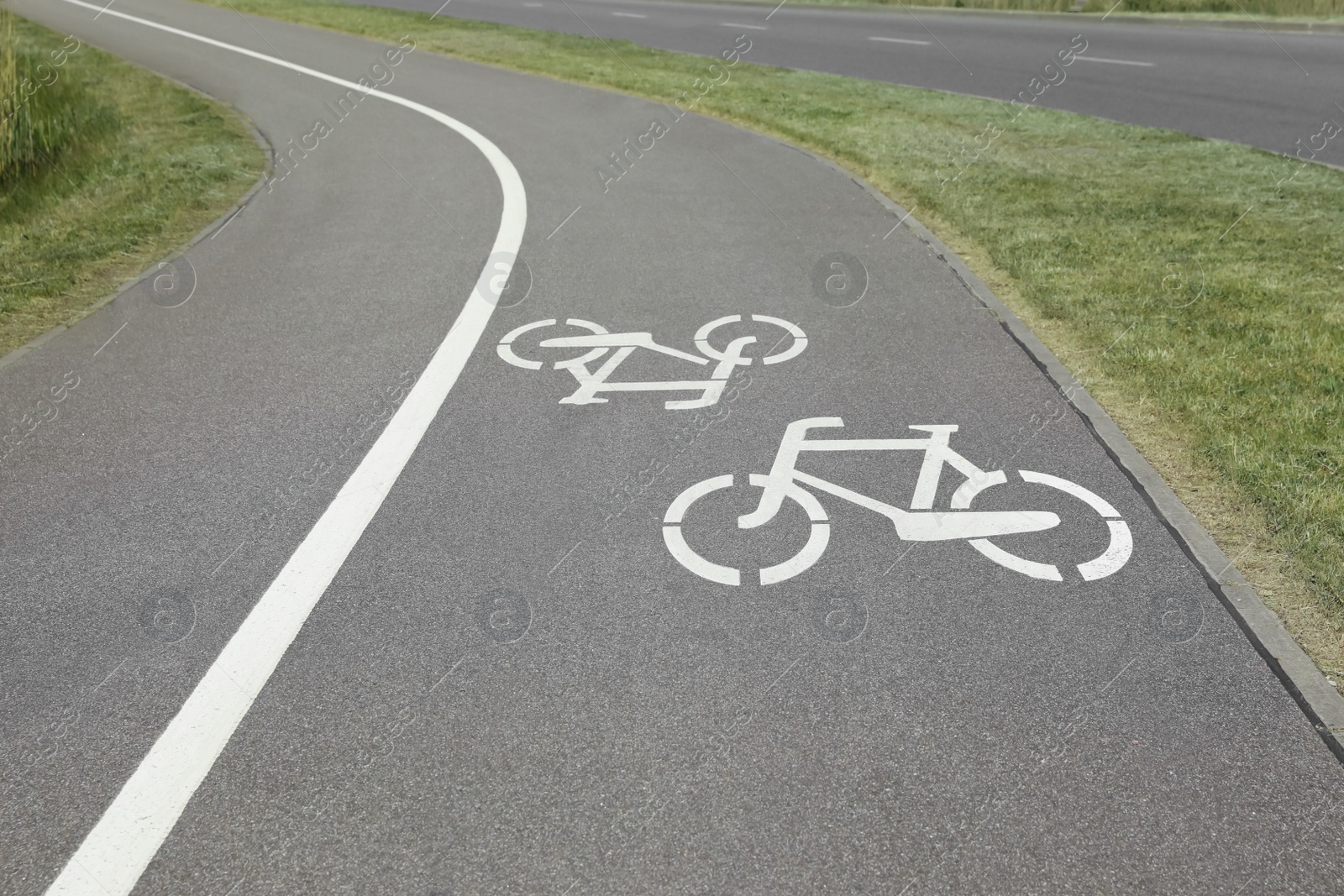 Photo of Bicycle lane with white sign painted on asphalt near sidewalk