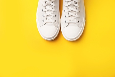 Photo of Pair of white sneakers on color background, top view