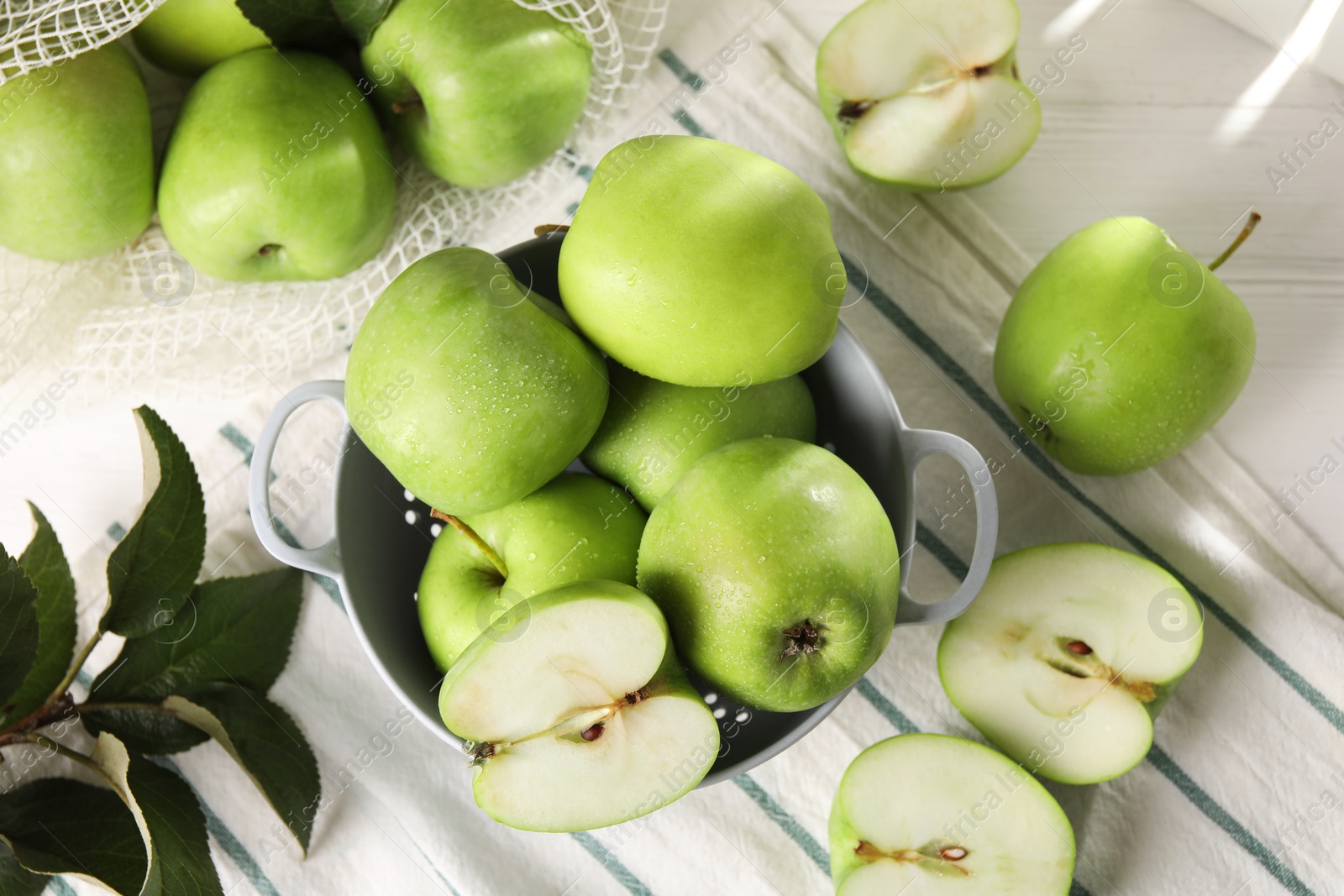 Photo of Fresh green apples with water drops and leaves on white wooden table, flat lay