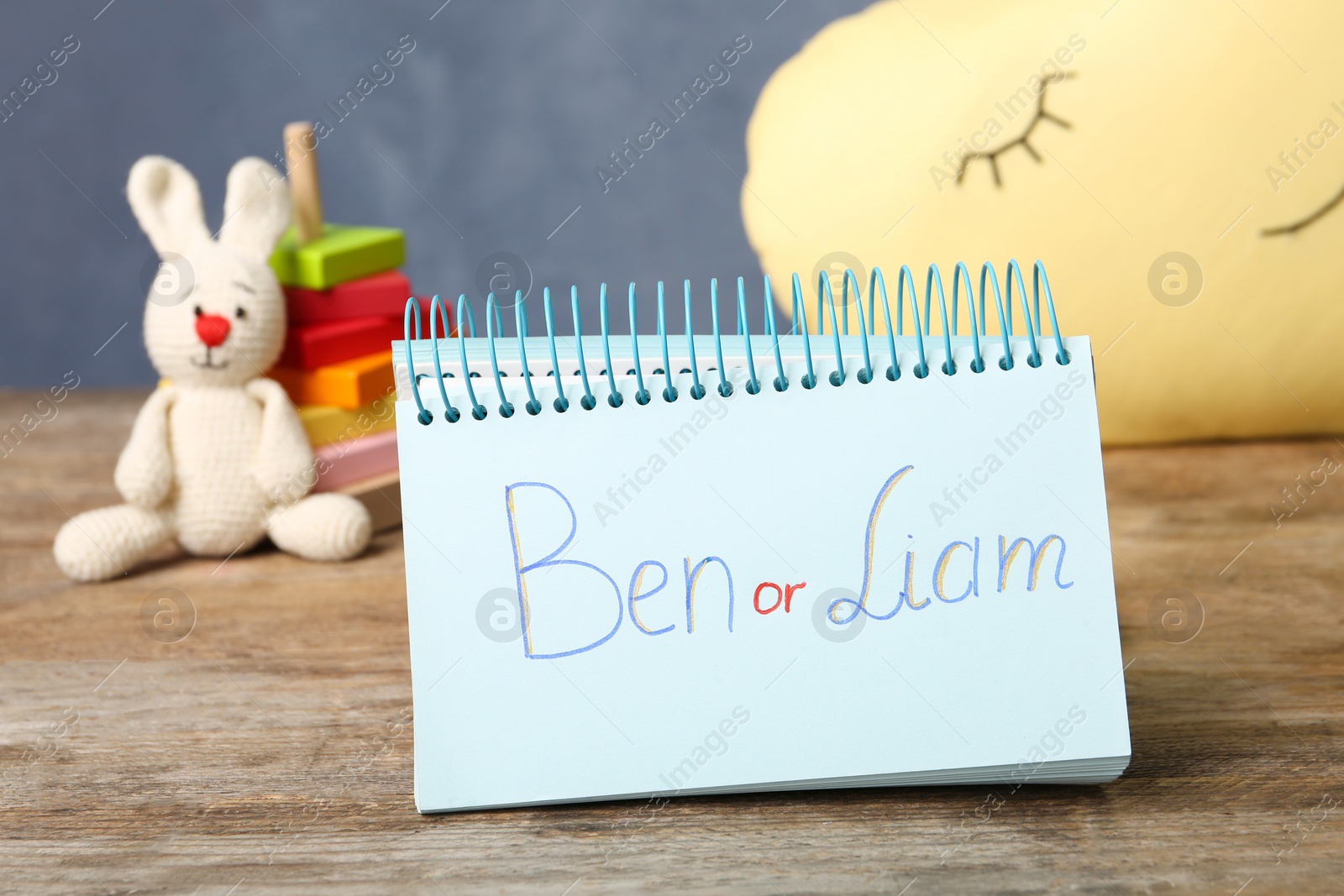 Photo of Notebook with different baby names on wooden table