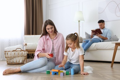 Photo of Mother playing with her daughter at home. Floor heating concept