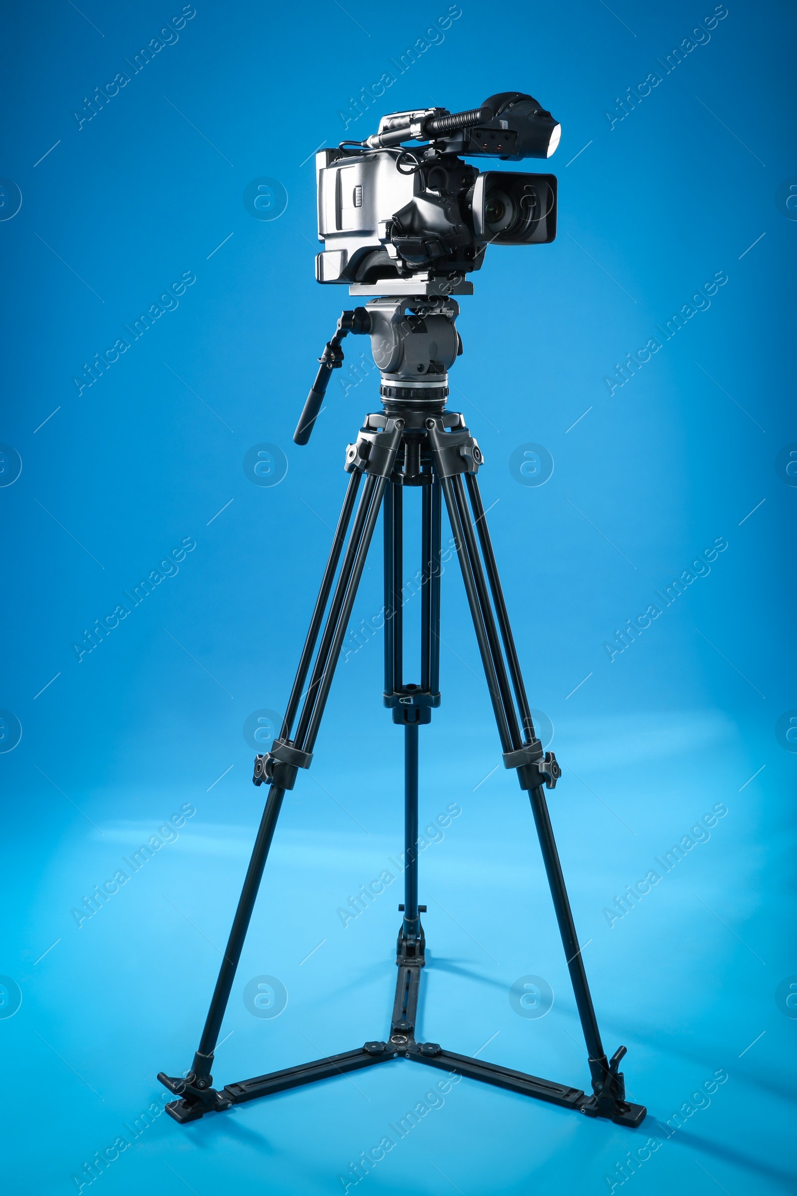 Photo of Modern professional video camera on blue background