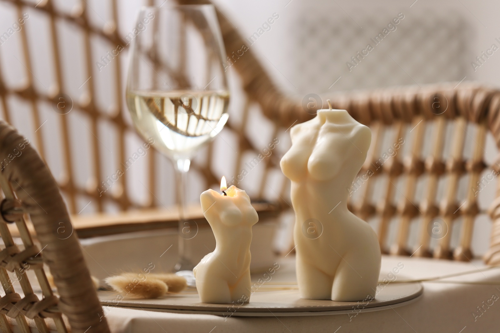 Photo of Beautiful body shaped candles and glass of wine on table indoors