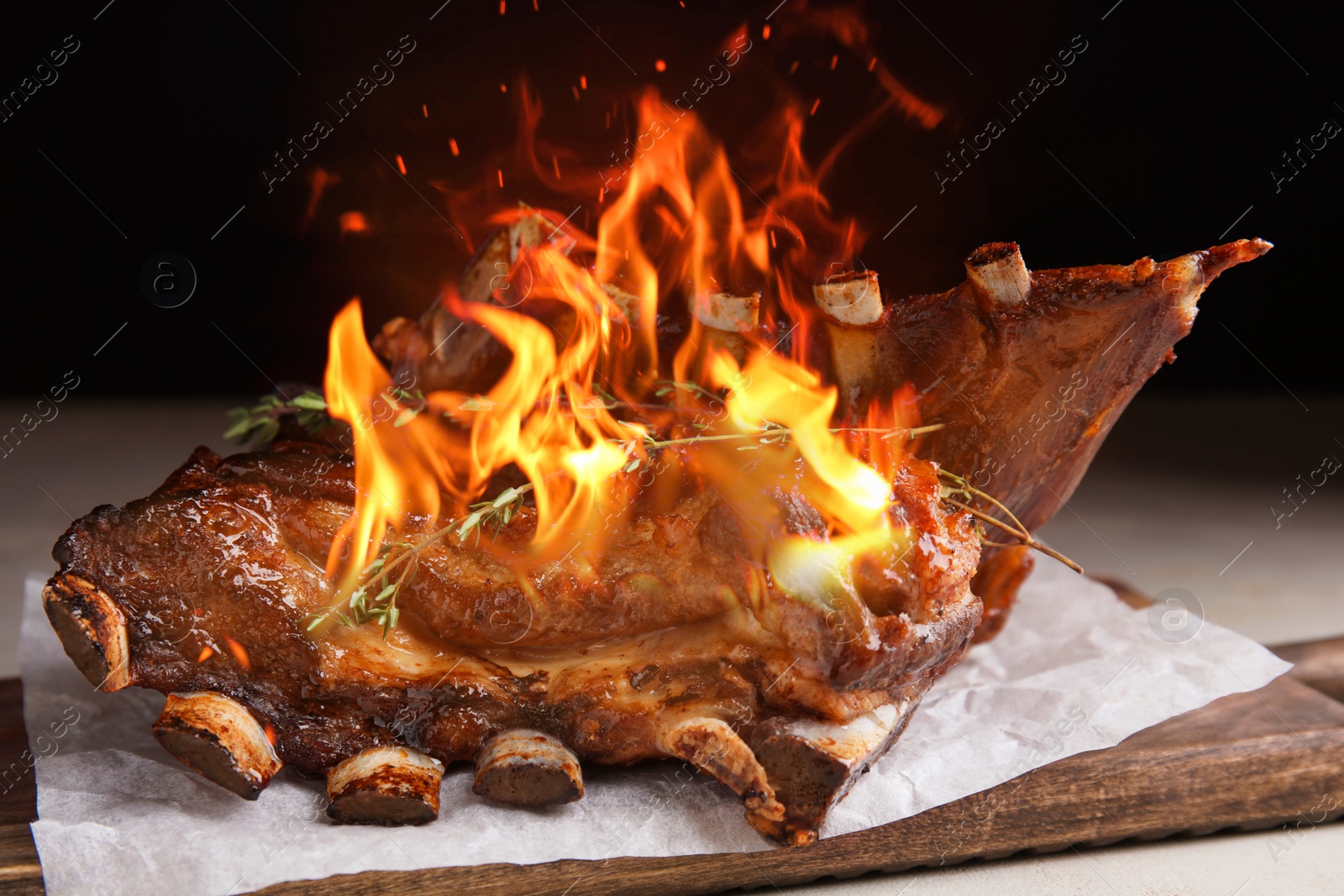 Image of Delicious roasted ribs with flame on table