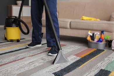 Photo of Mature man hoovering carpet with vacuum cleaner in living room