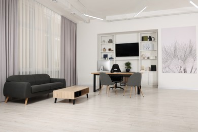 Photo of Stylish director's workplace with comfortable furniture and tv zone in room. Interior design
