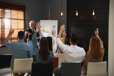 People raising hands to ask questions at seminar in office