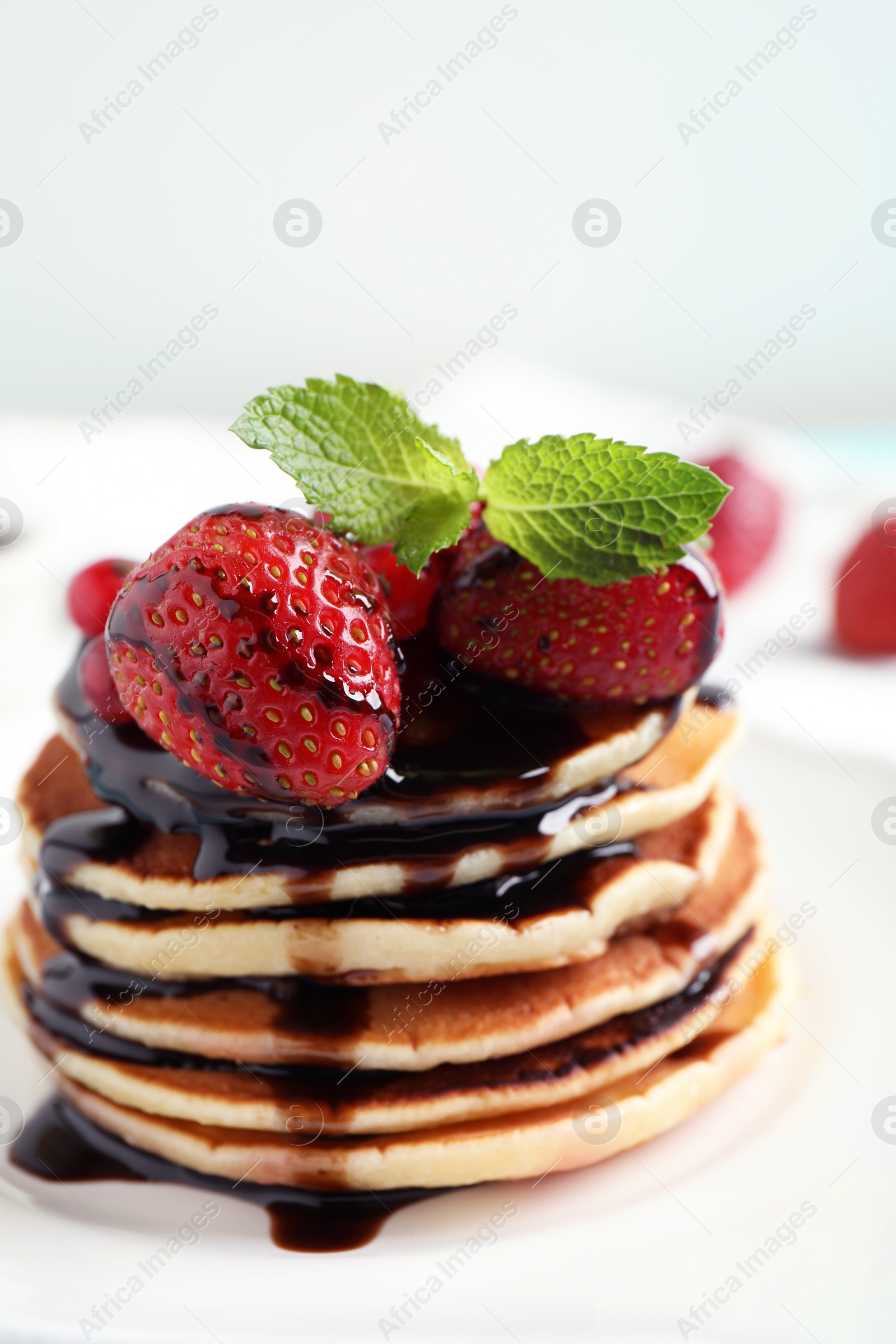 Photo of Delicious pancakes with fresh strawberries and chocolate syrup on table