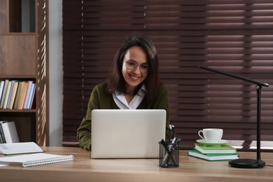 Woman with modern laptop learning at table indoors