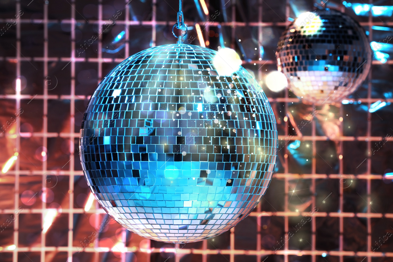 Image of Shiny disco balls against foil party curtain under color lights, bokeh effect