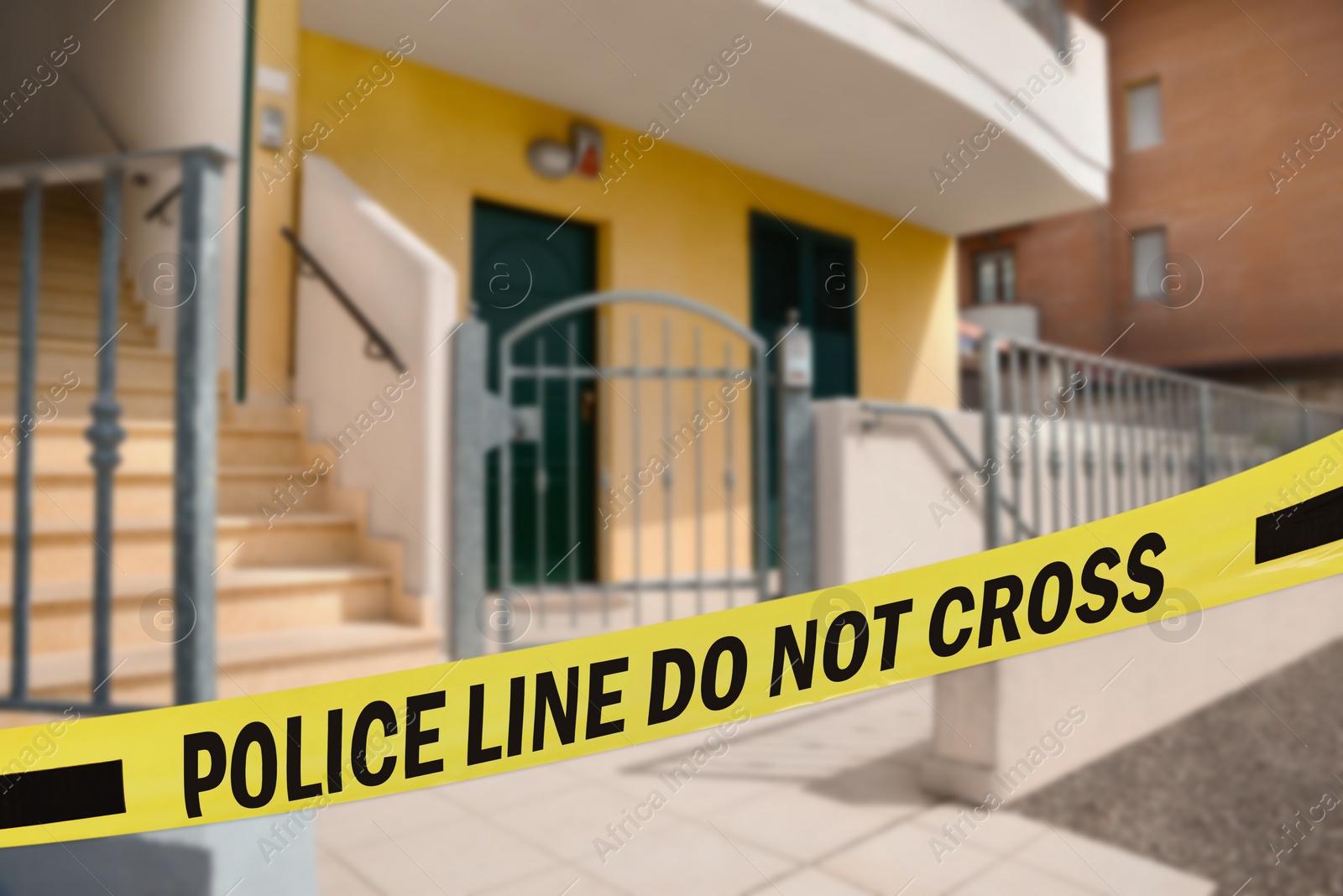 Image of Yellow crime scene tape blocking way to house outdoors