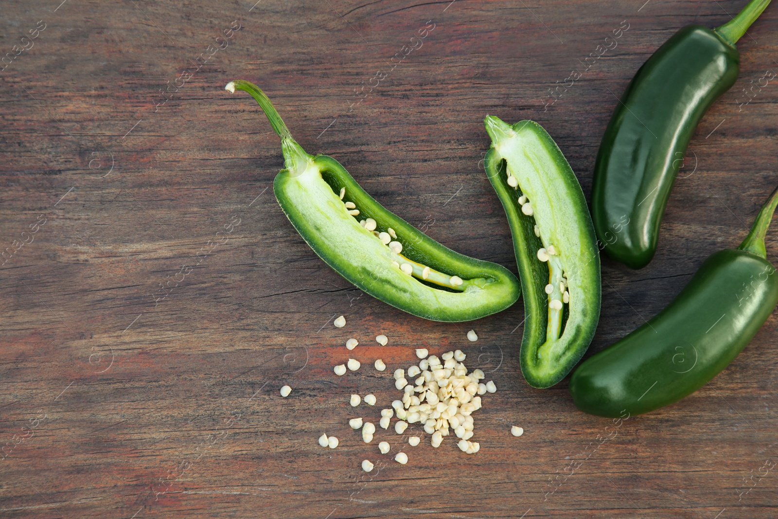 Photo of Fresh green jalapeno peppers and seeds on wooden table, flat lay. Space for text