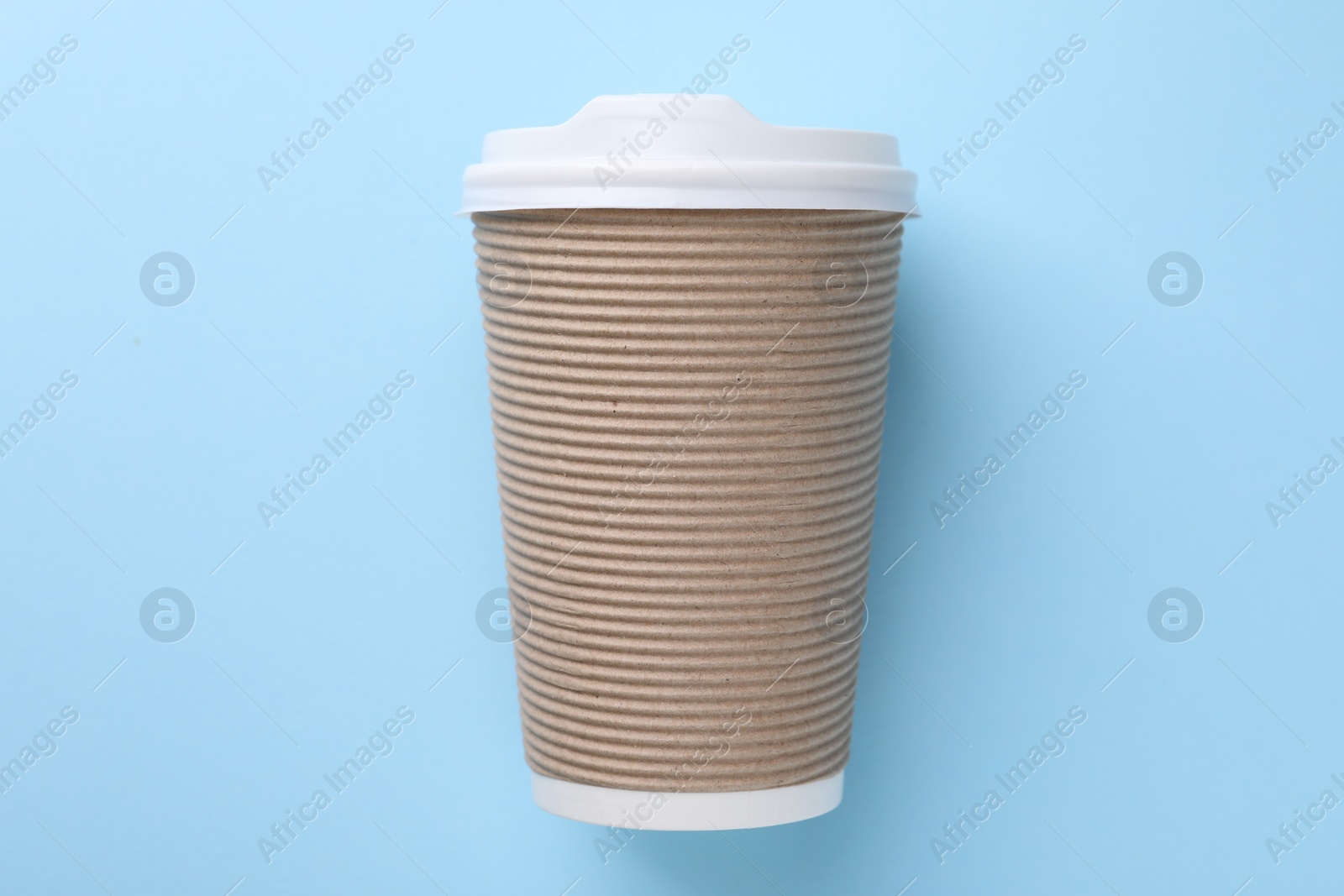 Photo of One paper cup on light blue background, top view. Coffee to go
