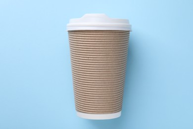 One paper cup on light blue background, top view. Coffee to go