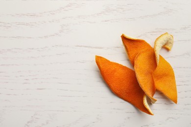 Photo of Dry orange peels on wooden table, top view. Space for text