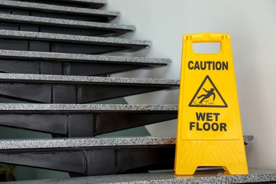 Photo of Safety sign with phrase Caution wet floor on stairs. Cleaning service