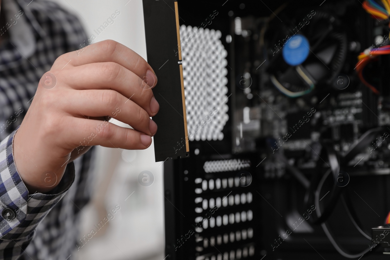 Photo of Male technician putting RAM chip into system unit, closeup. Computer repair