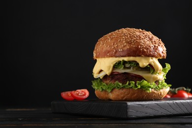 Photo of Vegetarian burger with delicious patty on black wooden table. Space for text