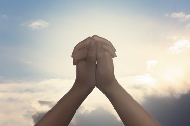 Image of Religion. Christian woman praying against sky, closeup