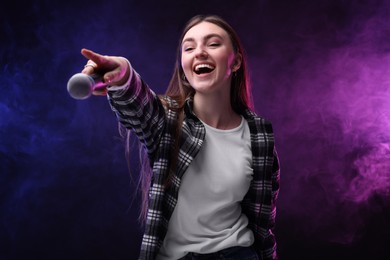 Photo of Emotional woman with microphone singing in color lights