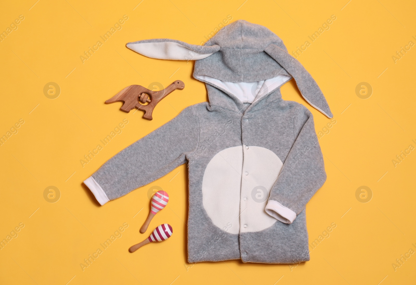 Photo of Child's clothes and toys on yellow background, flat lay