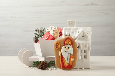 Photo of Composition with tasty gingerbread cookies on white wooden table. St. Nicholas Day celebration