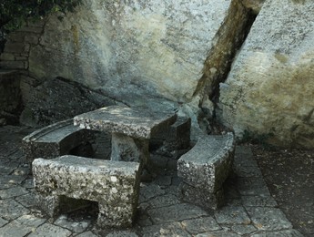 Photo of Stone table and benches near rock outdoors