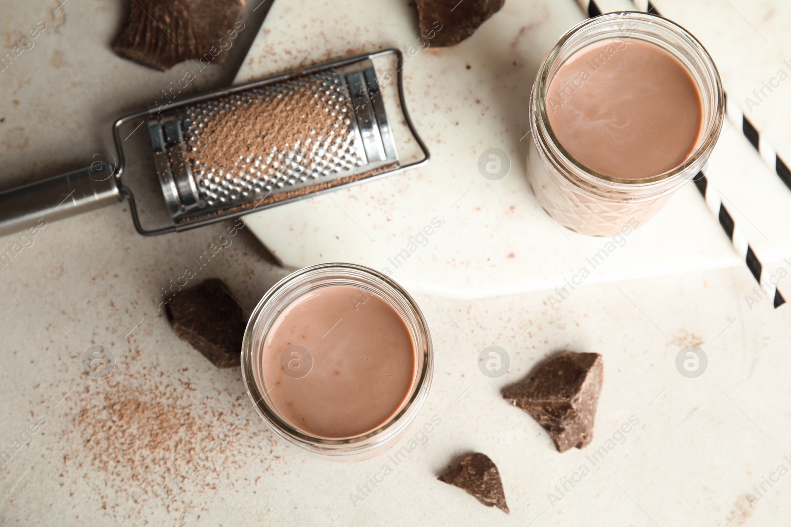 Photo of Flat lay composition with jars of tasty chocolate milk on light background. Dairy drink