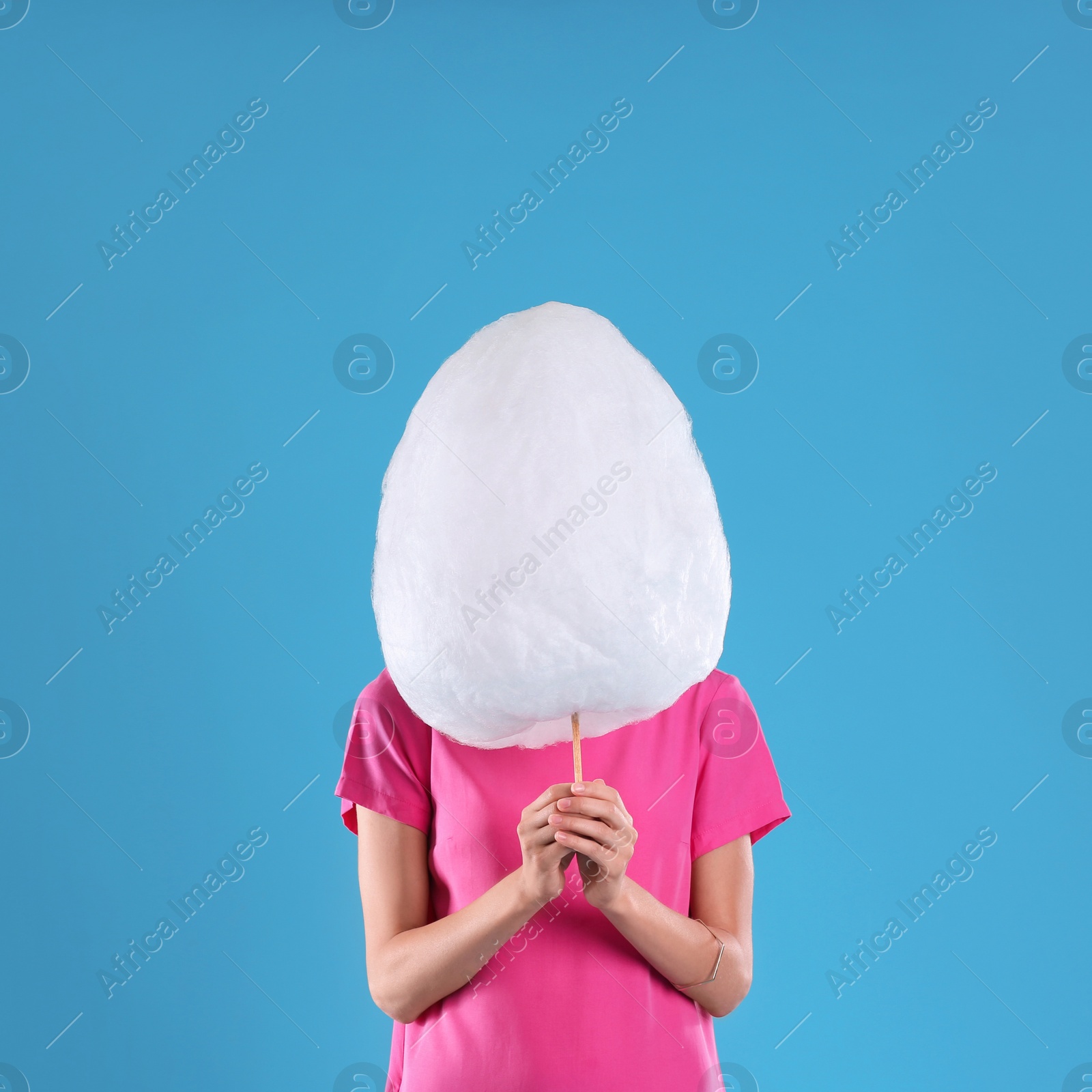 Photo of Young woman with cotton candy on blue background