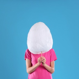 Photo of Young woman with cotton candy on blue background