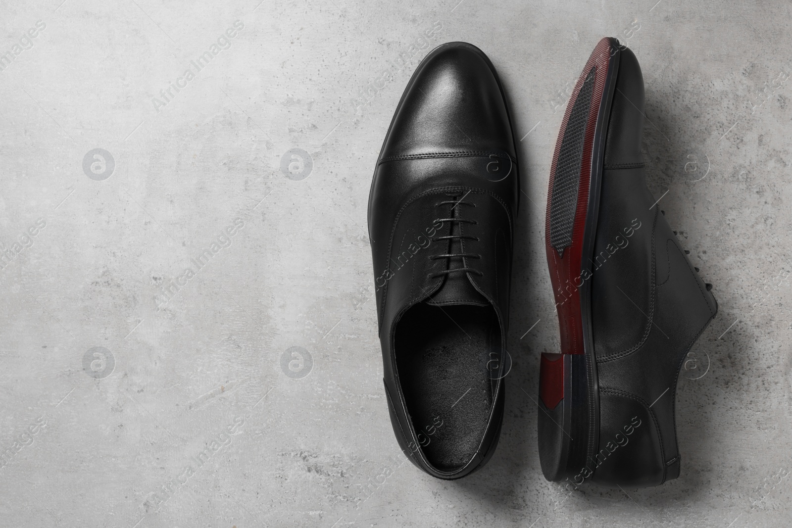 Photo of Pair of black leather men shoes on light grey surface, top view. Space for text