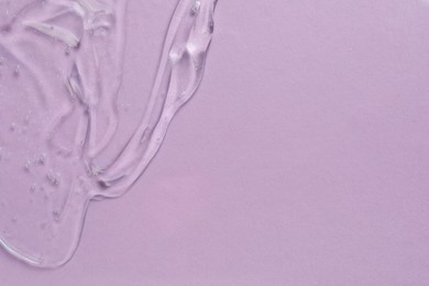 Clear cosmetic gel on light violet background, top view. Space for text