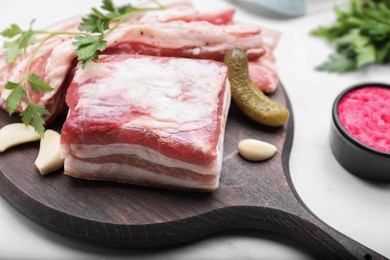 Tasty pork fatback with pickled cucumber, garlic and parsley on white table, closeup