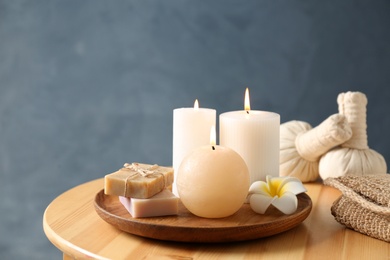 Spa composition with candles and cosmetic products on wooden table, space for text