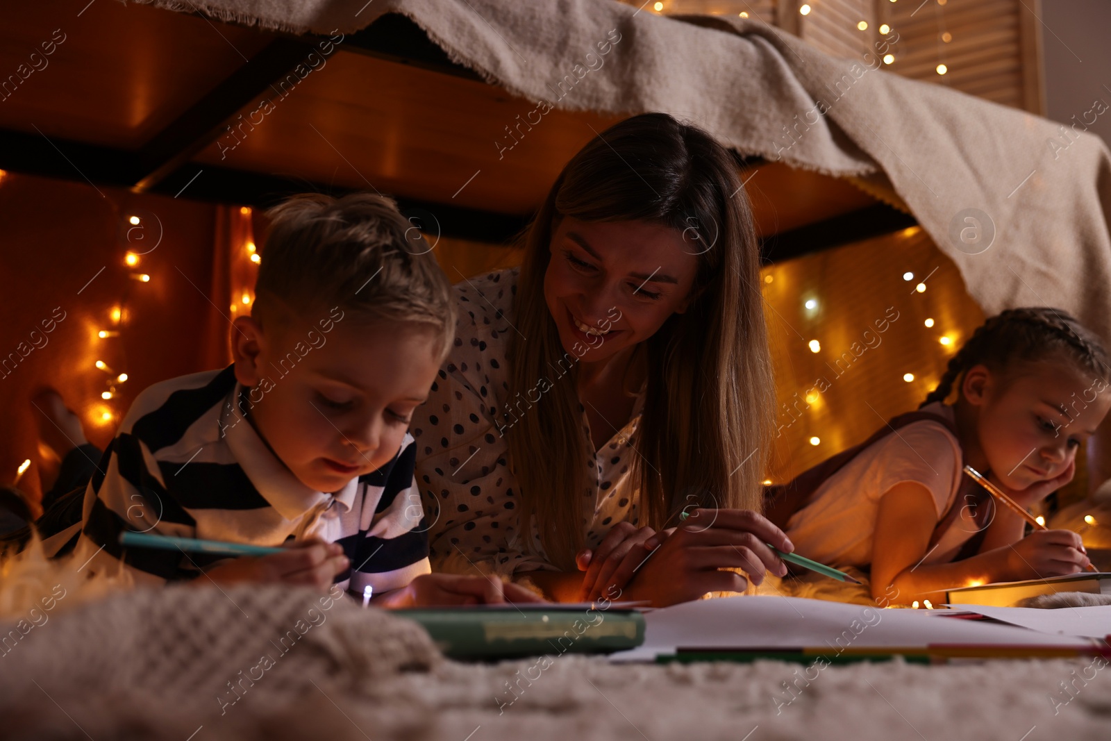 Photo of Mother and her children drawing in play tent at home