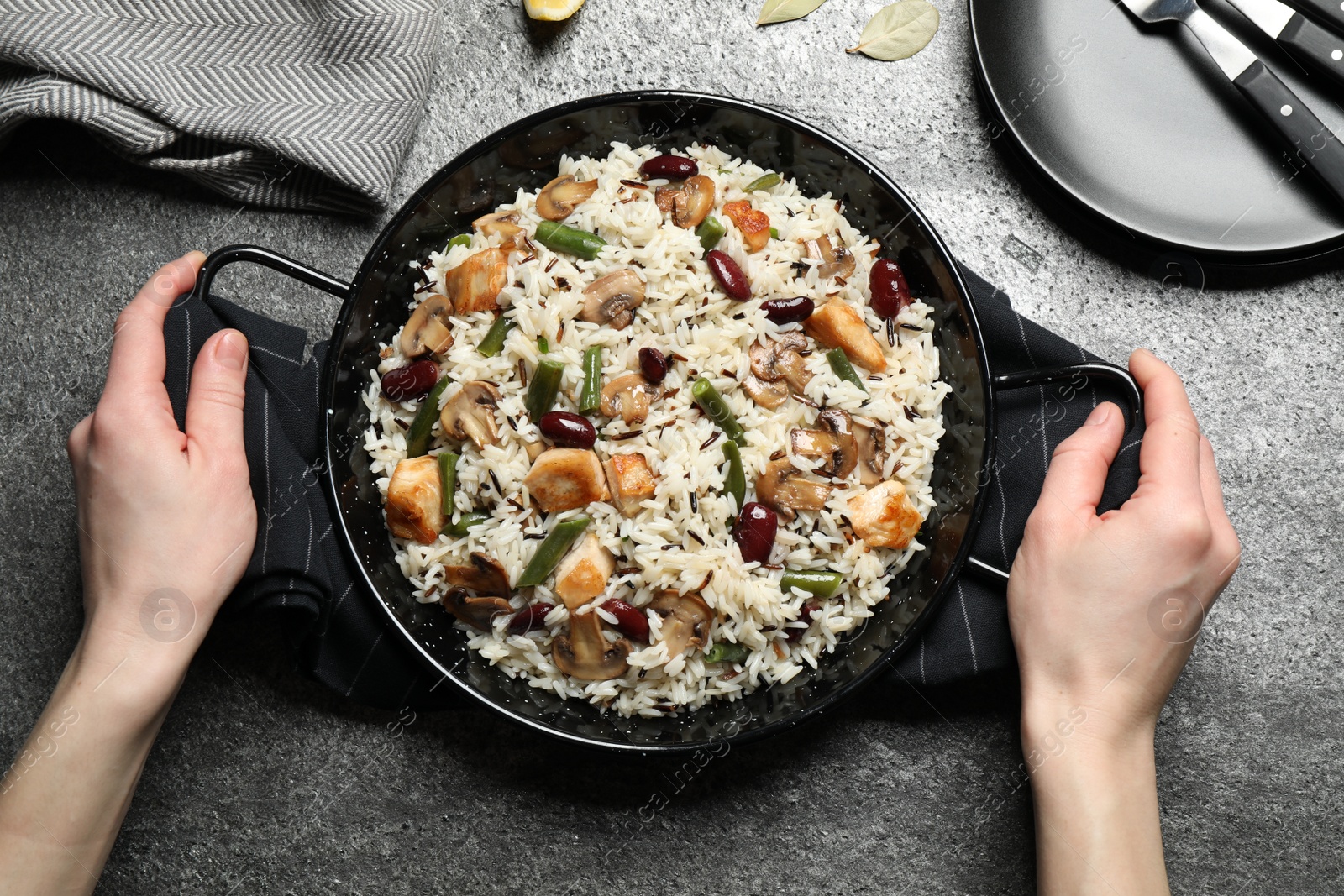 Photo of Woman with delicious rice pilaf at grey table, top view