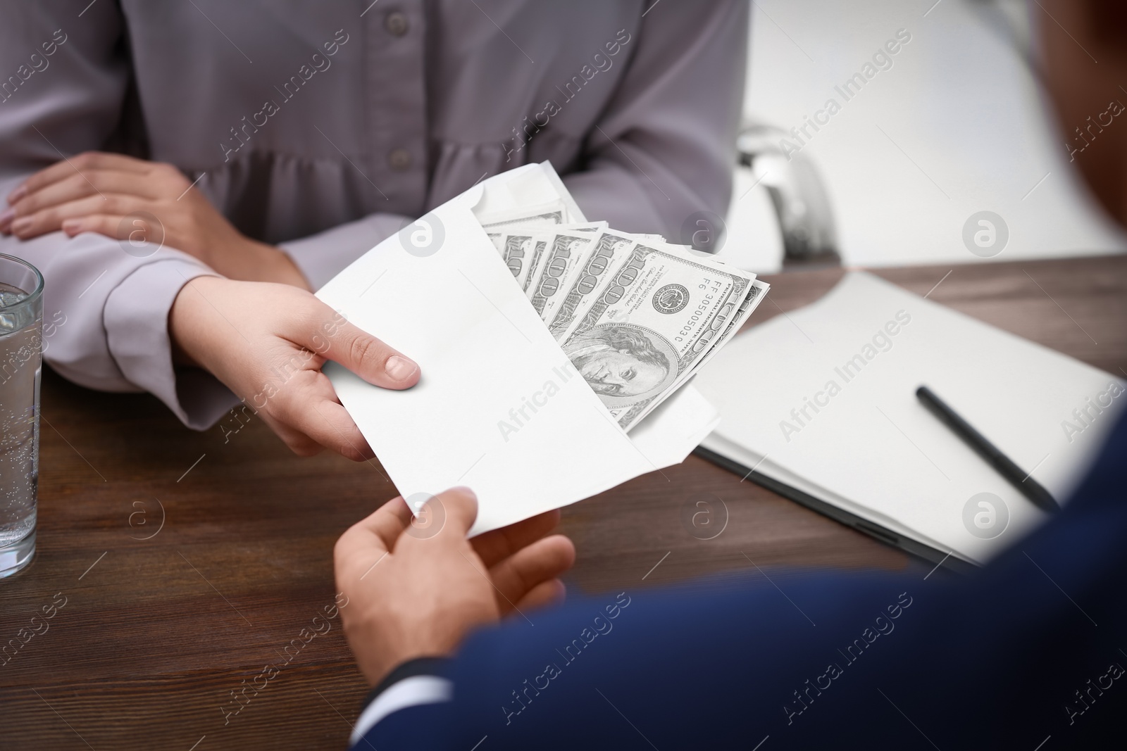 Photo of Man giving bribe money to woman at table, closeup