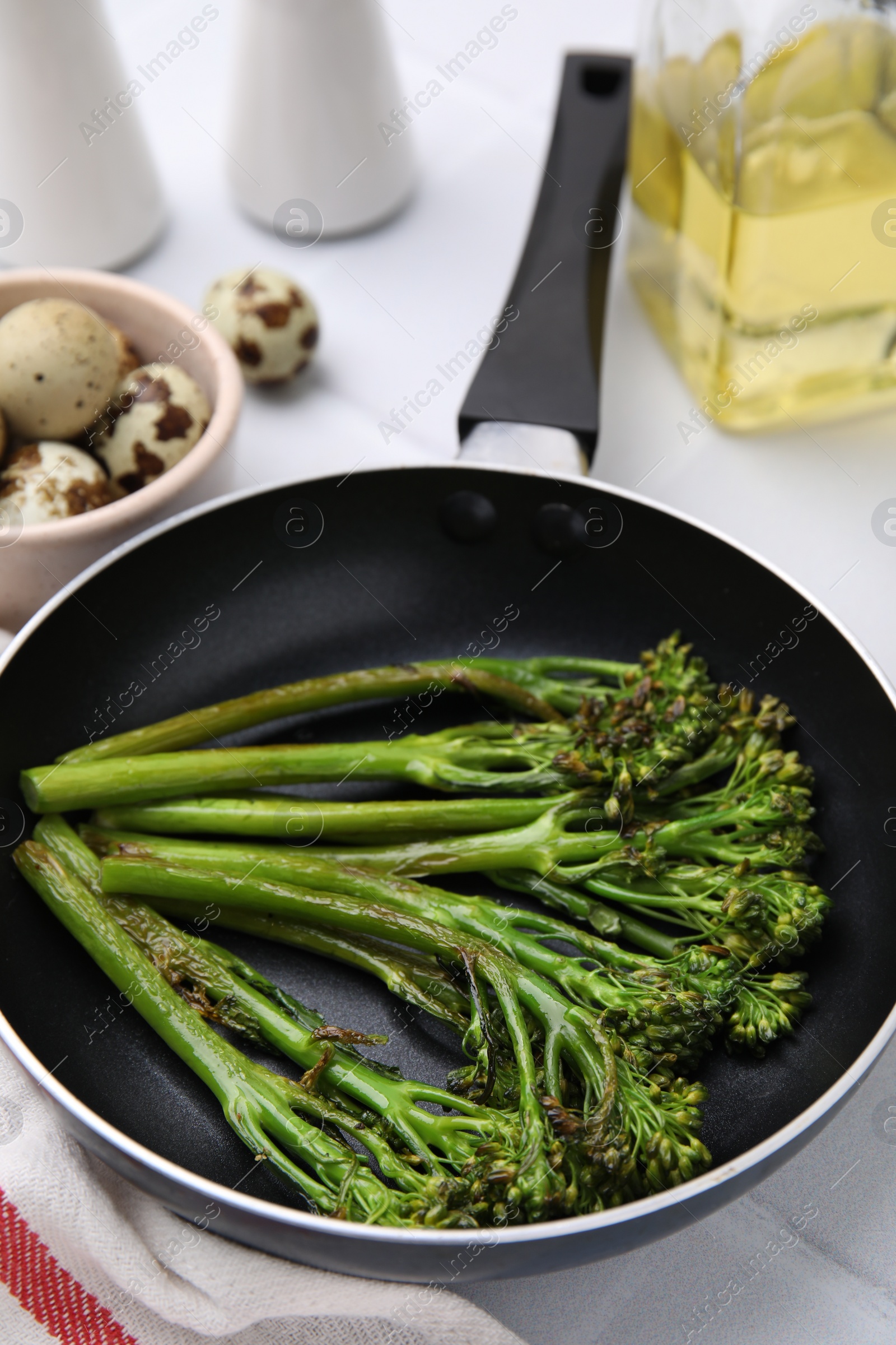 Photo of Frying pan with tasty cooked broccolini on table, closeup