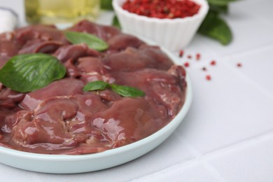 Photo of Plate of raw chicken liver on white tiled table, closeup