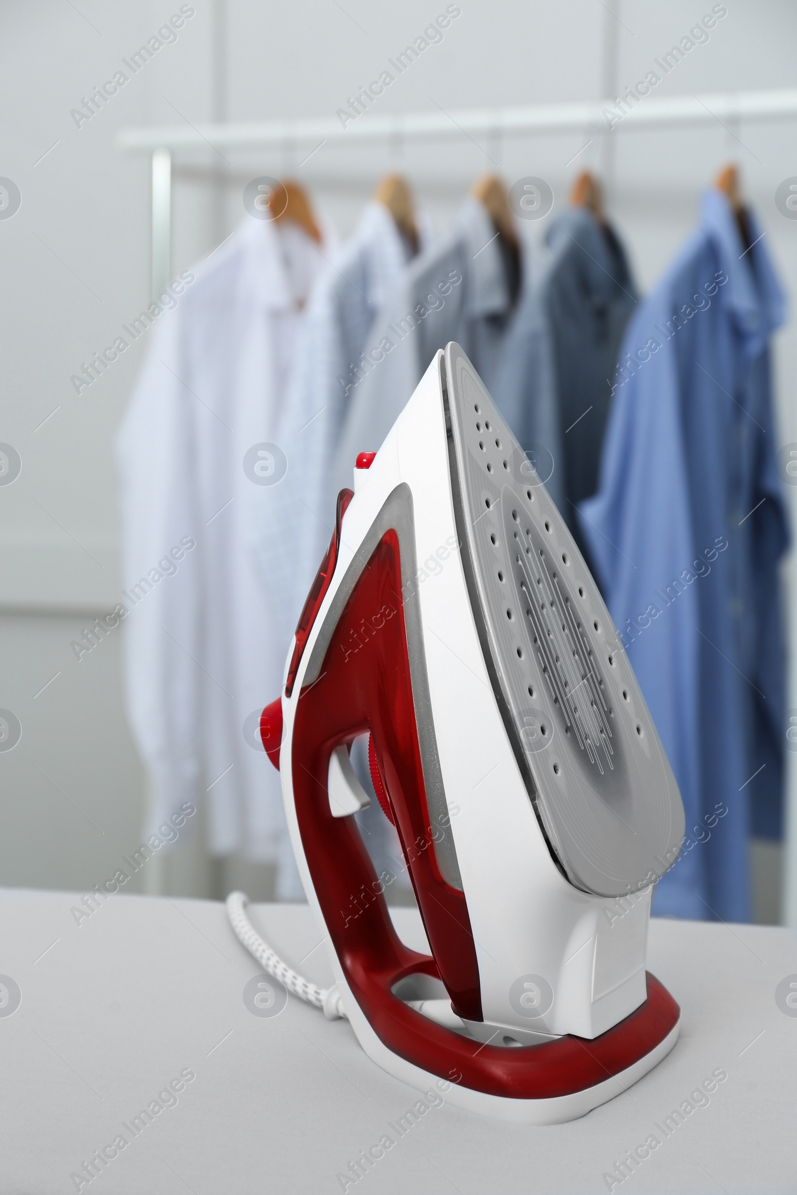 Photo of Modern iron on light table against blurred background