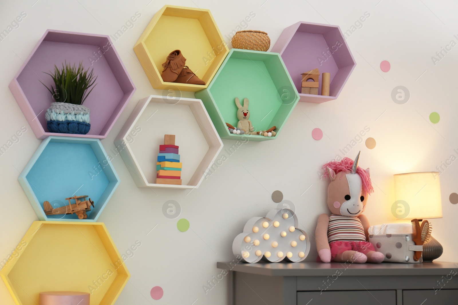 Photo of Bright colorful shelves on light wall in room. Interior design