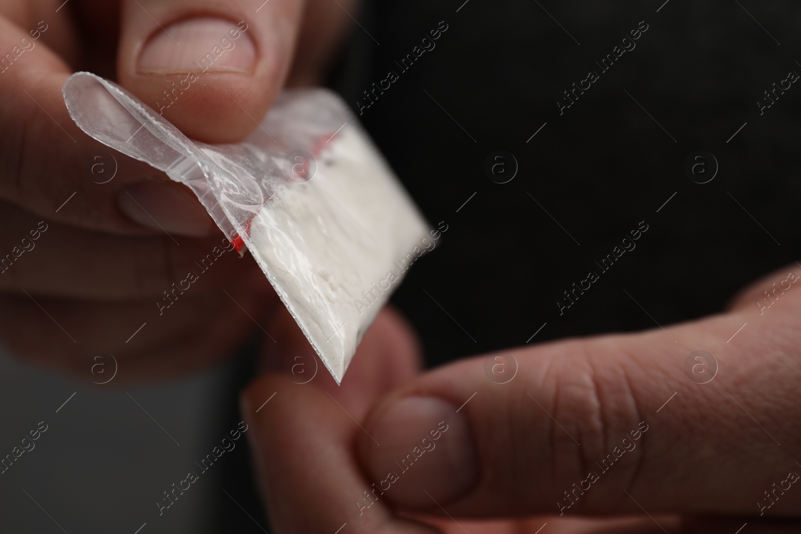 Photo of Drug addiction. Man with plastic bag of cocaine on grey background, closeup