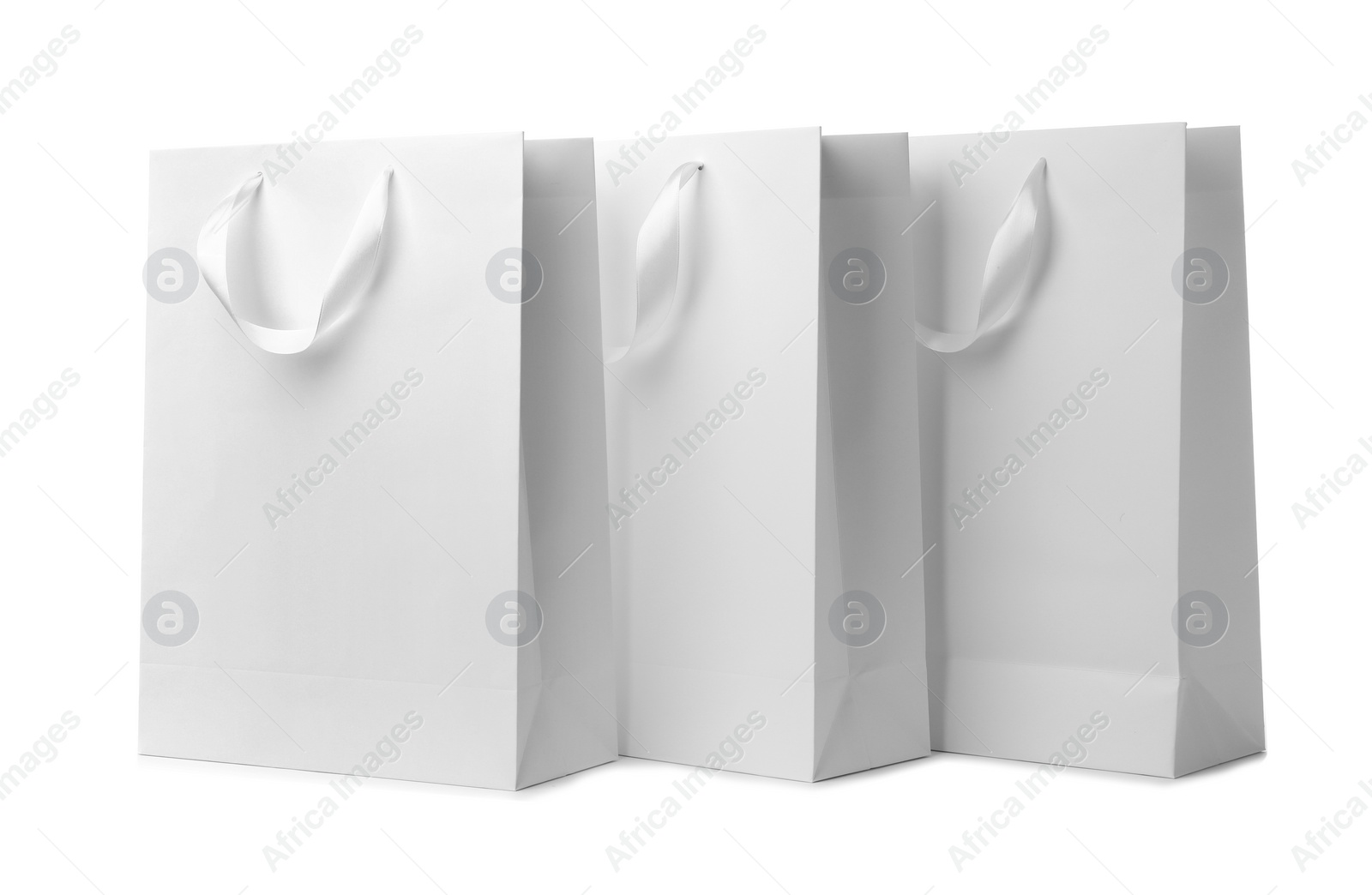 Photo of Paper shopping bags with ribbon handles on white background. Mockup for design