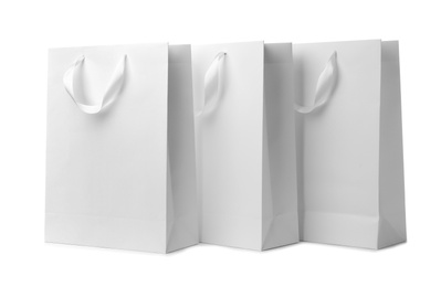 Paper shopping bags with ribbon handles on white background. Mockup for design