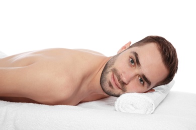 Handsome man relaxing on massage table against white background. Spa service