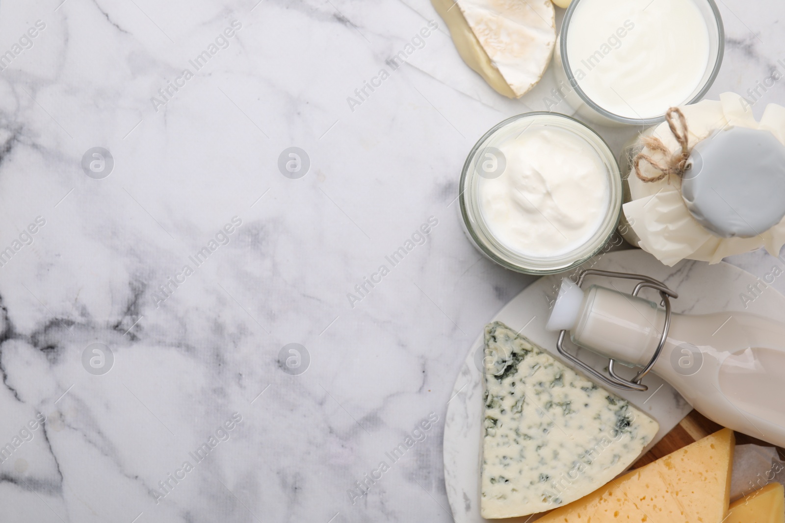 Photo of Different fresh dairy products on white marble table, top view. Space for text